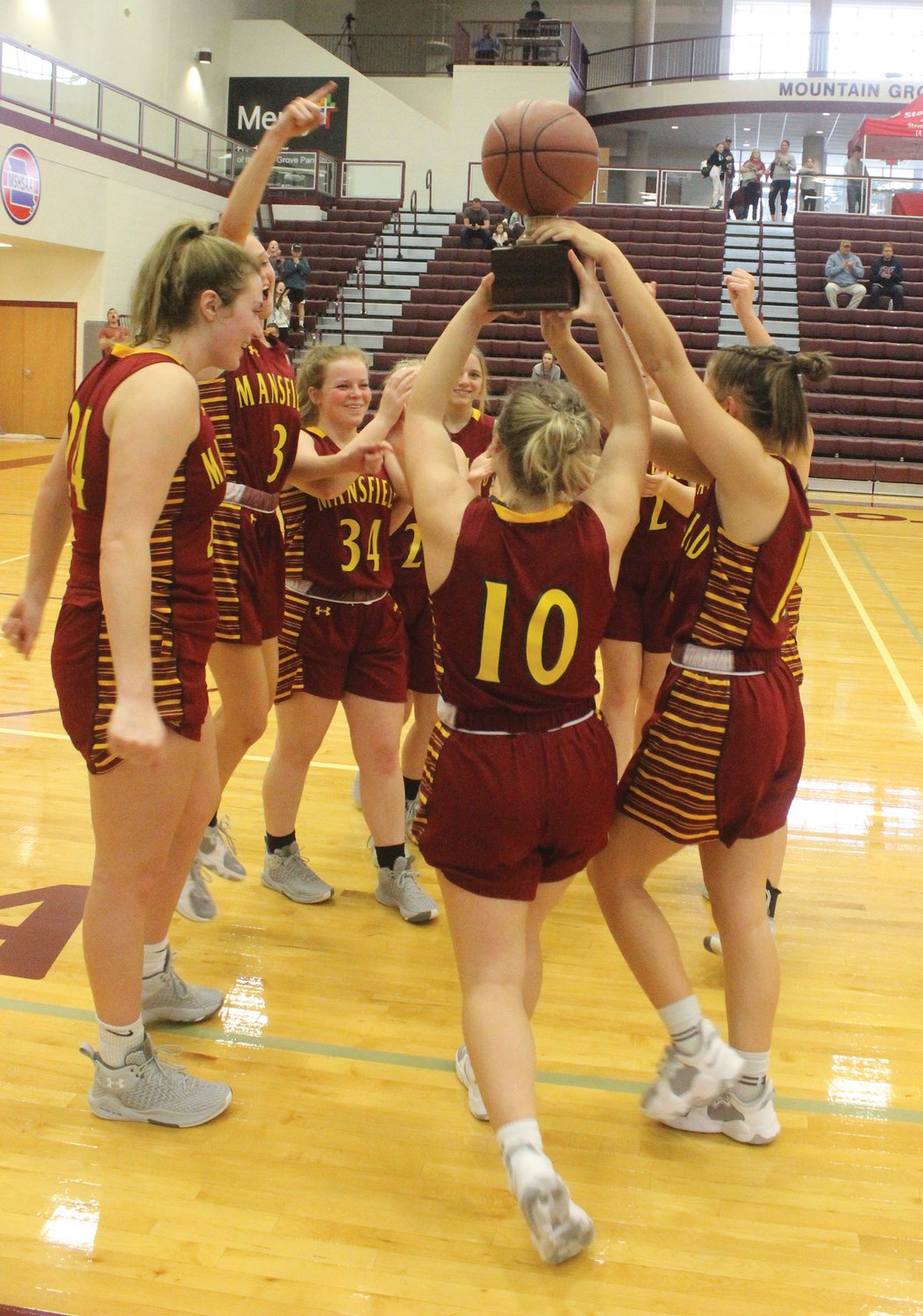 The Mansfield Lady Lions basketball team celebrates after defeating Salem to win their first ever State Farm Insurance Holiday Tournament in Mountain Grove.